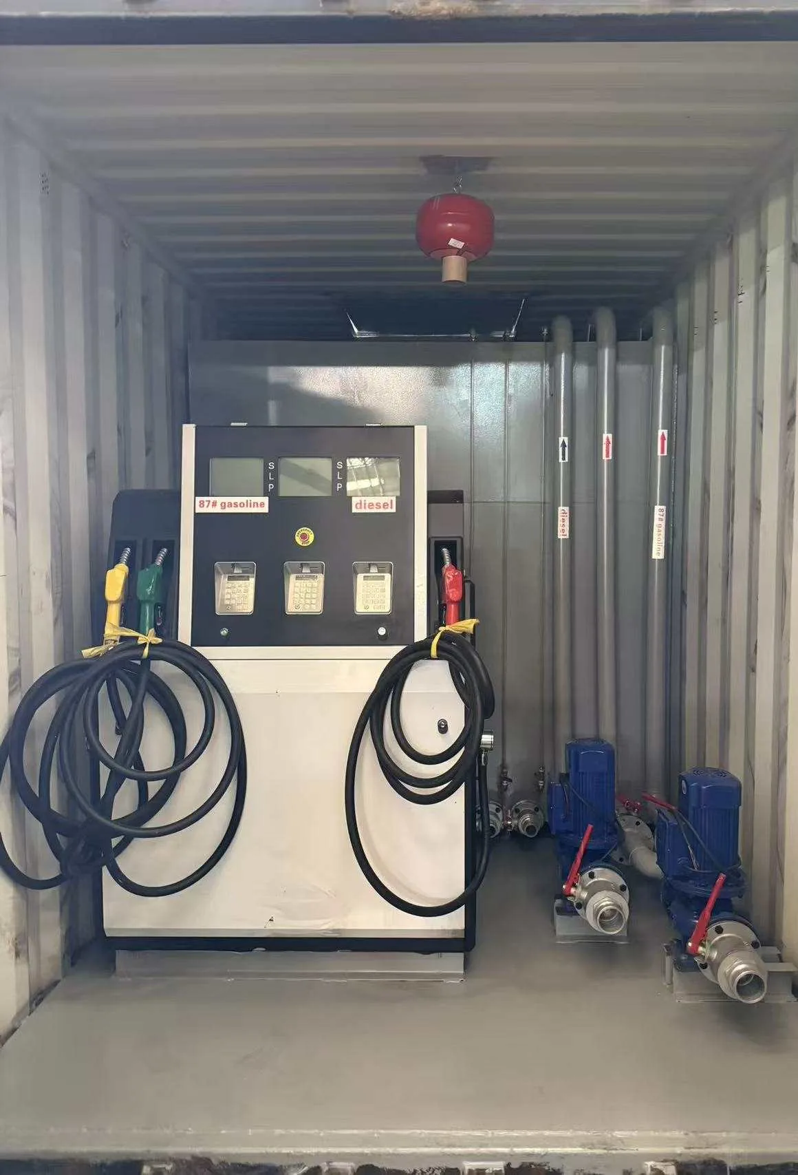 Containerized fuel station interior with a dispenser, pumps and project-specific pipework.